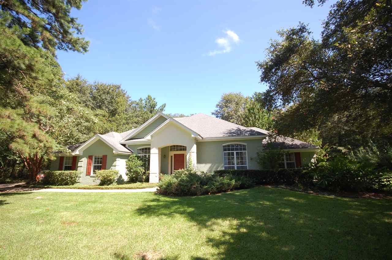 A spacious home surrounded by a large yard and mature trees, creating a serene and inviting outdoor environment.