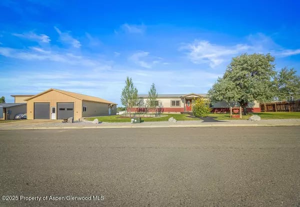 Single-story home with a detached garage, lawn, and mature tree across the street.