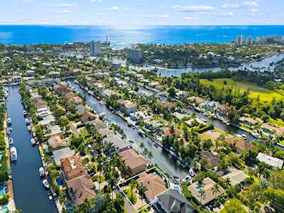 Aerial view of canal-side homes and waterways in Lighthouse Point, with the ocean in the distance.