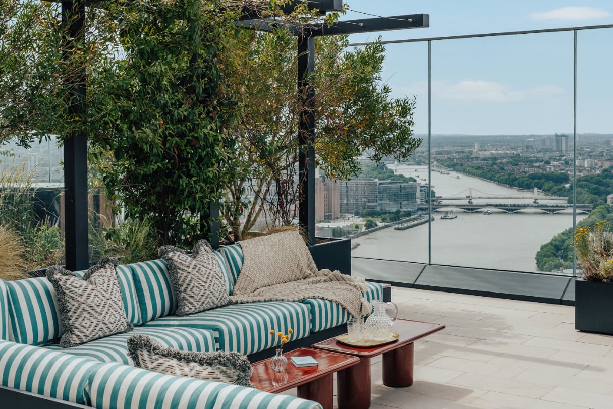 Rooftop terrace with striped seating overlooking the River Thames and London skyline.