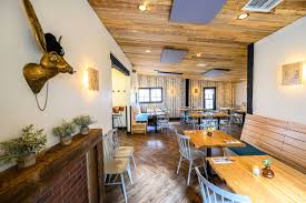 Restaurant interior with a wood ceiling, long banquette, and mounted animal head.