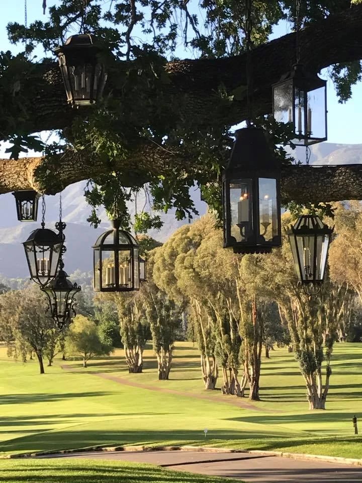 Hanging lanterns frame a manicured golf course with distant mountains.