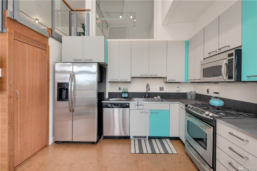 Sleek condo kitchen with stainless steel appliances and teal accents, exuding modern luxury living.