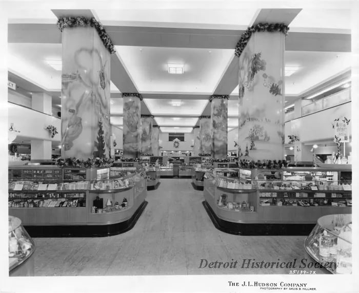 J.L. Hudson Company department store interior with curved display counters and tall decorated columns.