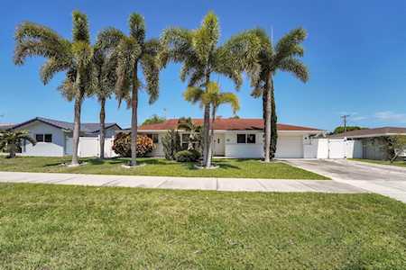Single-story home with a red tile roof and tall palm trees lining the front lawn.