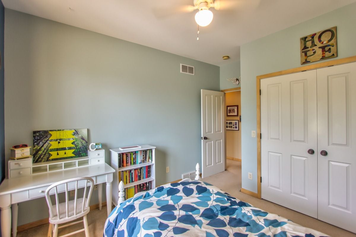 Bedroom with blue-and-white patterned bedding, a white desk and chair, and a small bookcase.