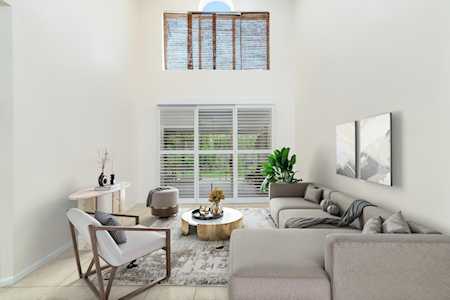Living room with a tall vaulted ceiling, large windows, and a light gray sectional sofa.