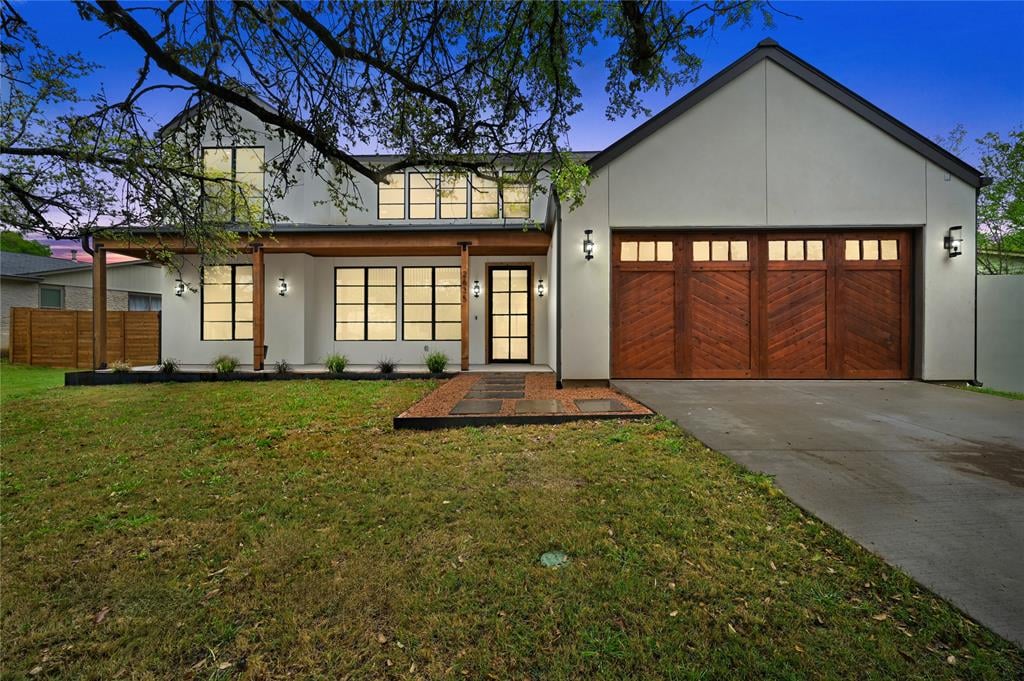 Twilight front elevation of the modern farmhouse home at 2635 Barton Hills Dr in Austin's Barton Hills neighborhood, with a wood garage door and covered entry.