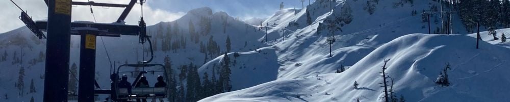 Snow-covered ski slopes and mountain peaks beside a chairlift.