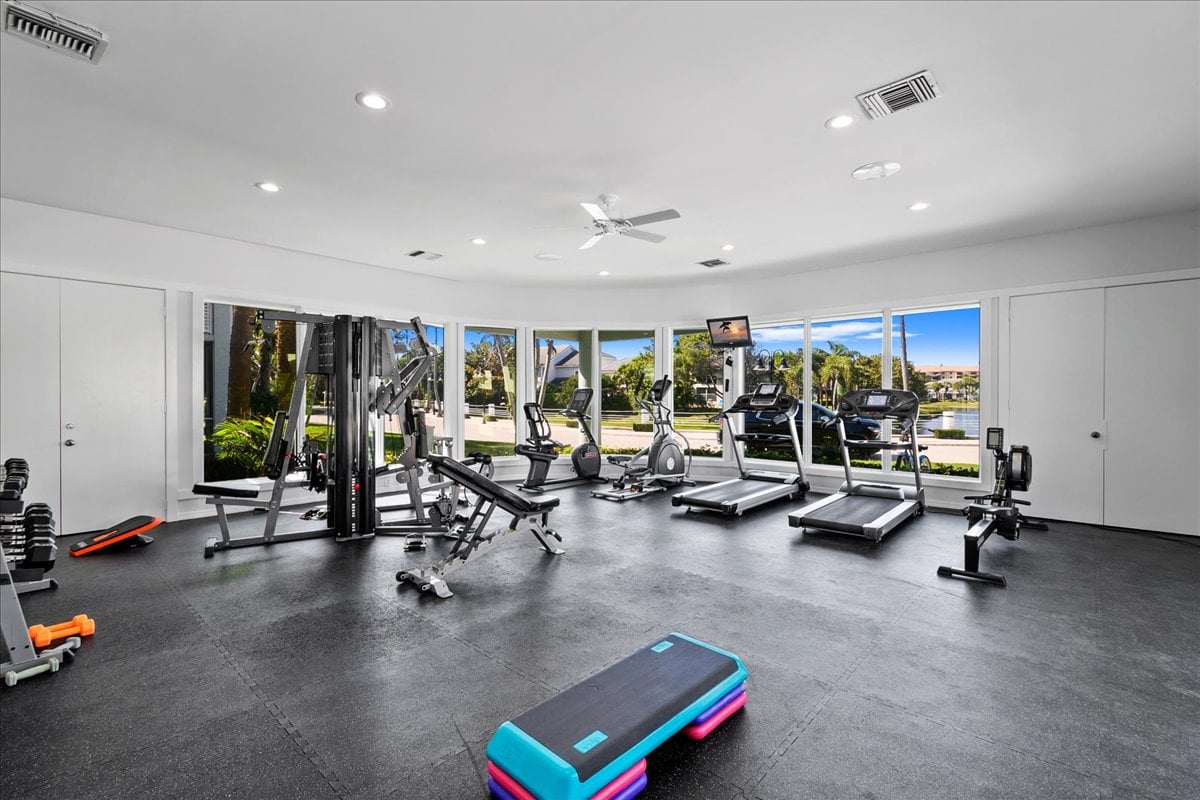 Condominium fitness center with weight machines, treadmills, and windows overlooking water.