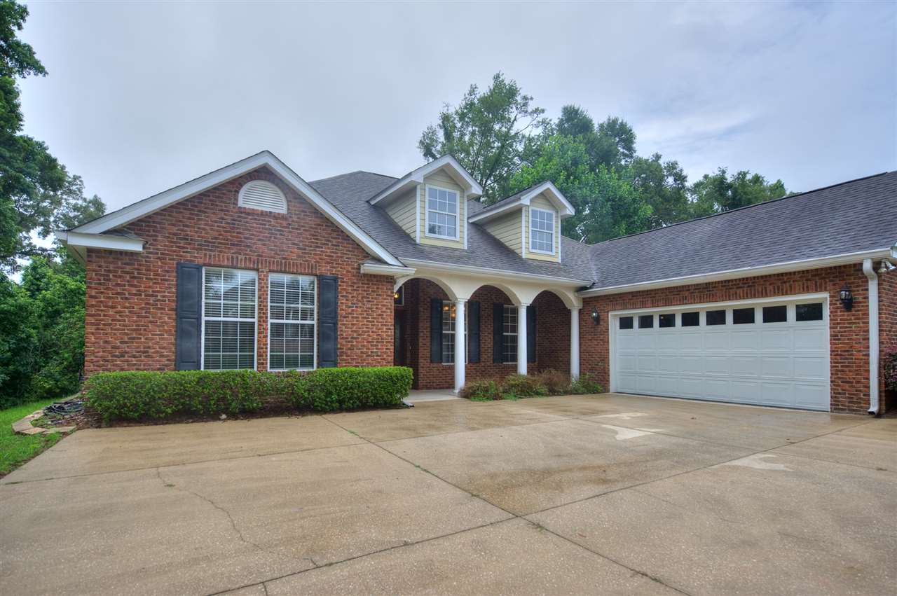 A brick home featuring a garage and a neatly paved driveway.