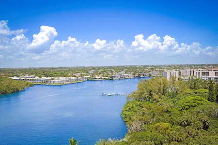 Aerial view of a broad blue waterway bordered by leafy homes and mid-rise buildings.