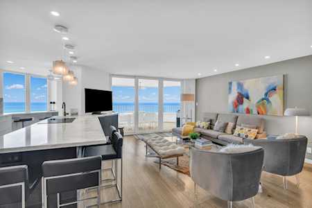 Open-plan kitchen and living room with gray seating and broad windows overlooking the water.