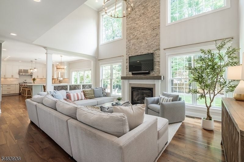 Living room with vaulted ceiling, stone fireplace, large windows, and light sectional sofa.