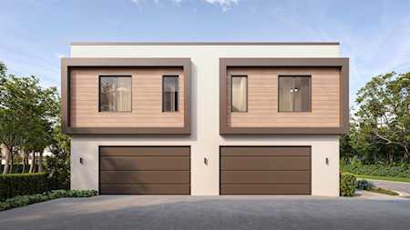 Modern two-unit building with wood-look façades and two double garage doors.