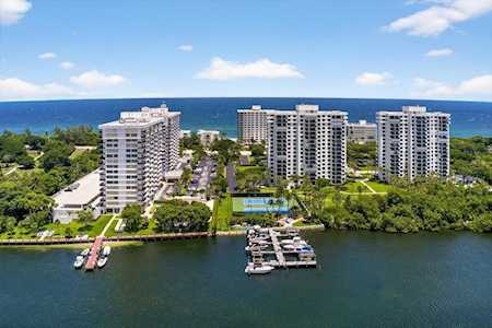 Waterfront condominium towers between the ocean and a waterway with docks and lush landscaping.