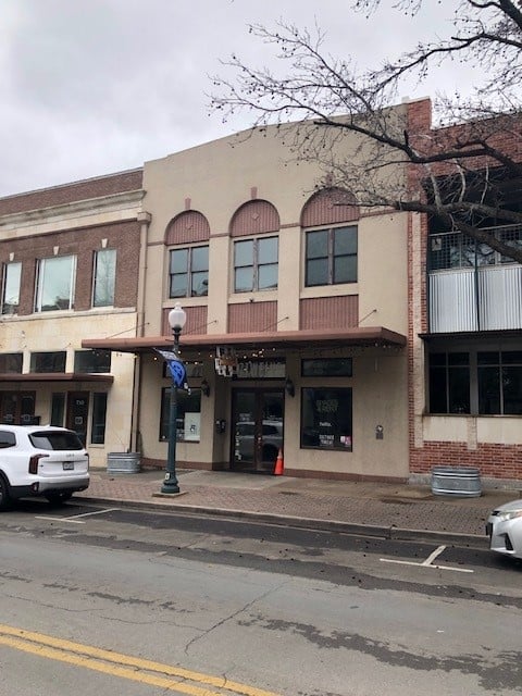 Two-story commercial building with arched upper windows and a covered street-level entrance.