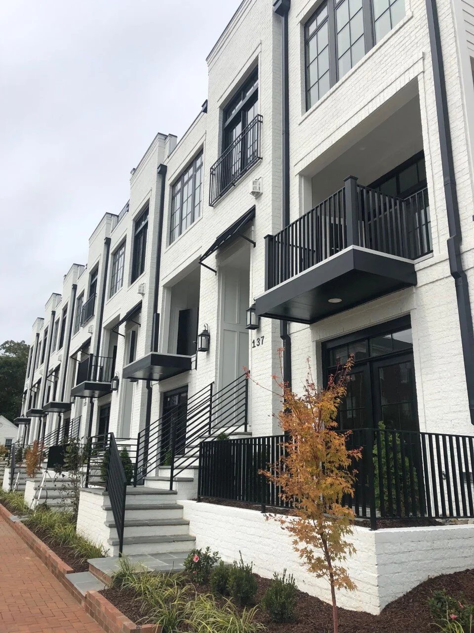 Brick three story townhomes with bay windows and metal roof accents at Park Station in downtown Cary