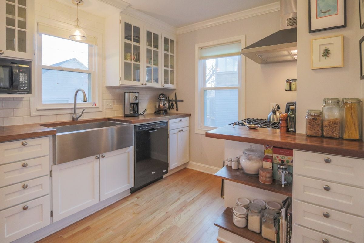 Kitchen with white cabinets, wood countertops, and a large stainless farmhouse sink.