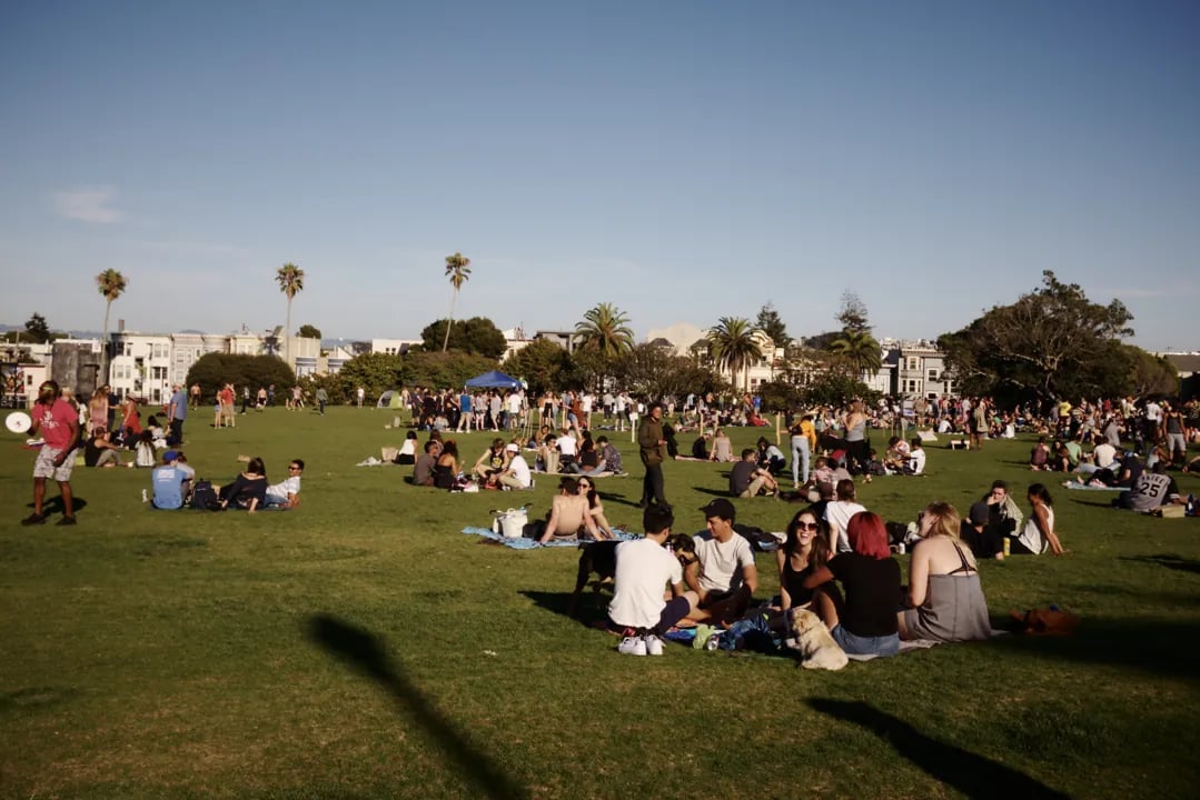People picnicking on the lush green lawns of Mission Dolores Park