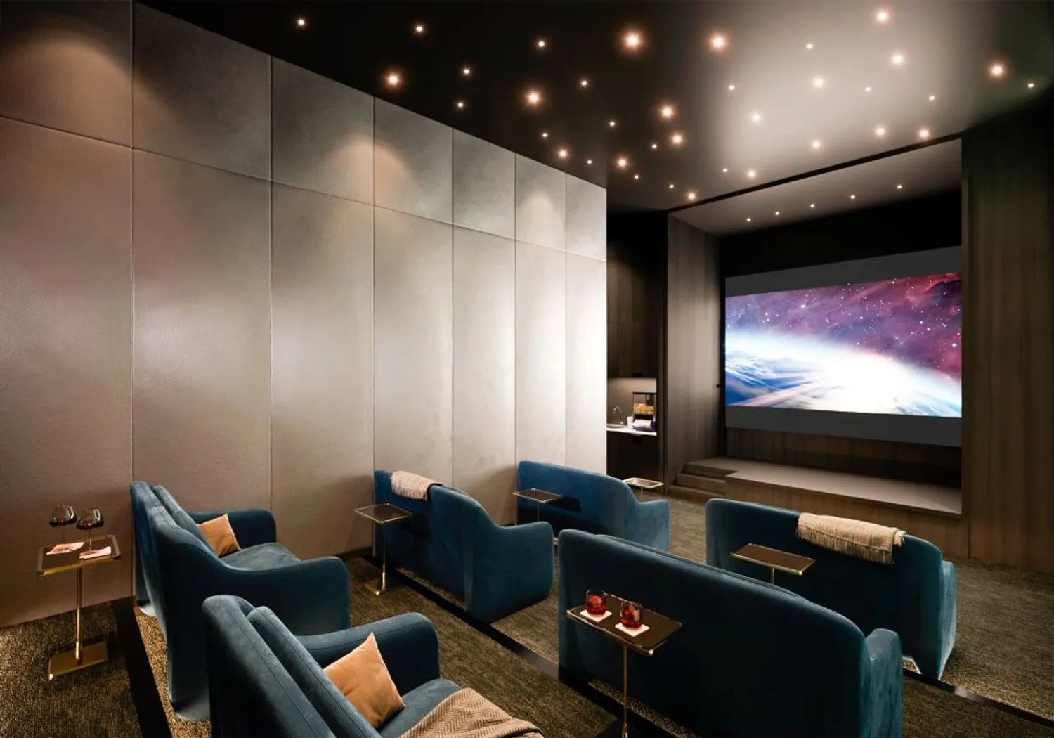 Furnished screening room with blue lounge chairs facing a large projection screen.