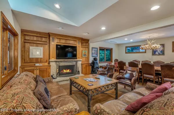Furnished living room with a wood-paneled television wall, fireplace, and adjacent dining area.