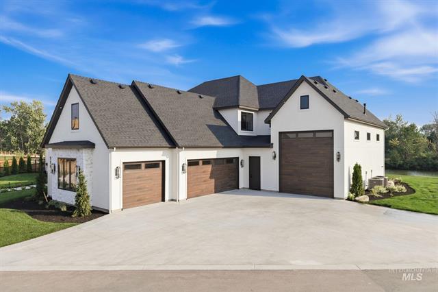 White two-story home with three wood-tone garage doors and a broad concrete driveway.