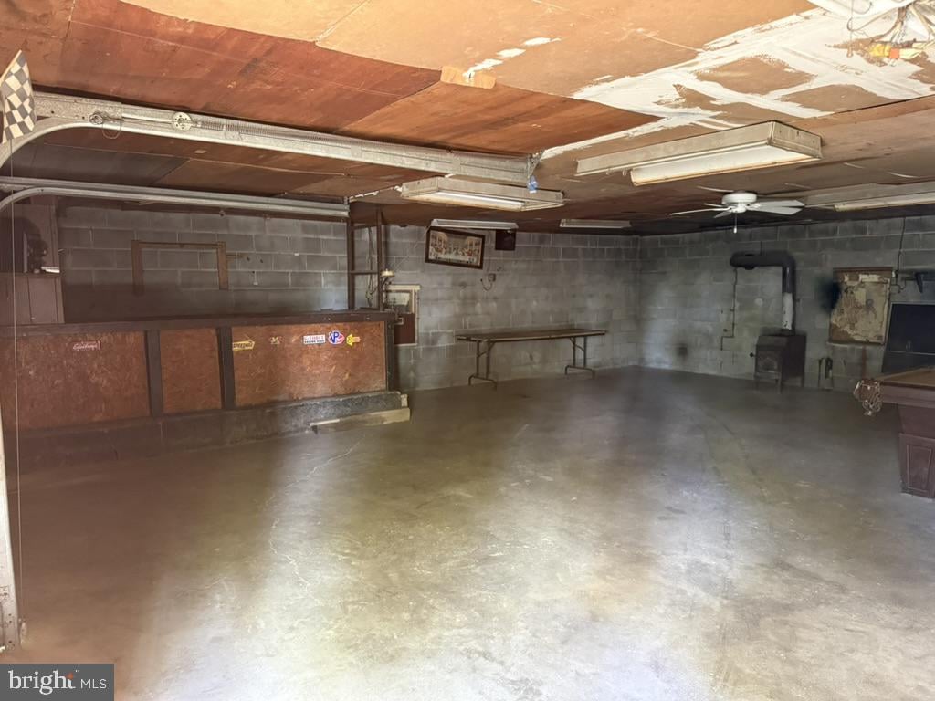 Basement recreation room with a wooden bar, concrete floor, and cinder-block walls.