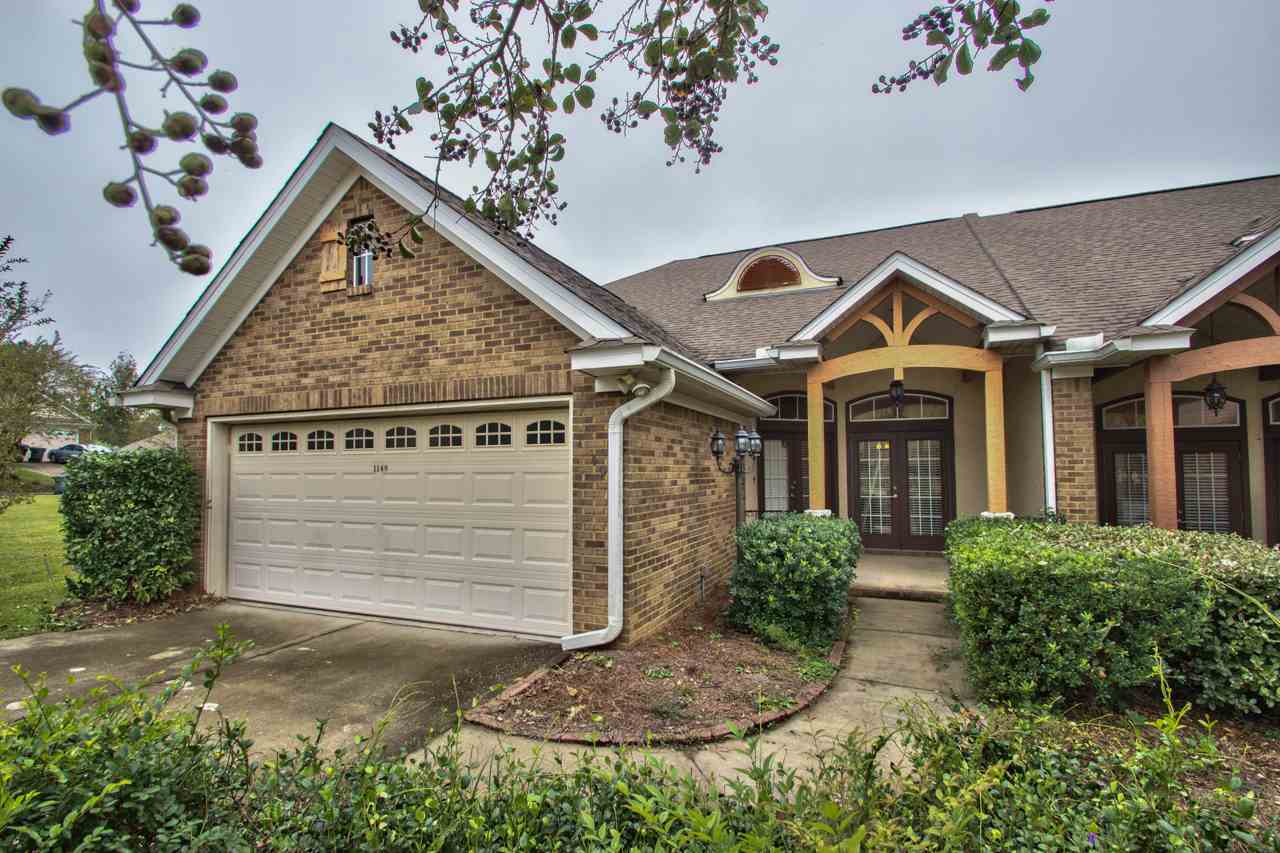 A brick home featuring a garage and a neatly paved driveway.