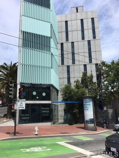 Modern corner building with a pale turquoise louvered facade and gray concrete tower.