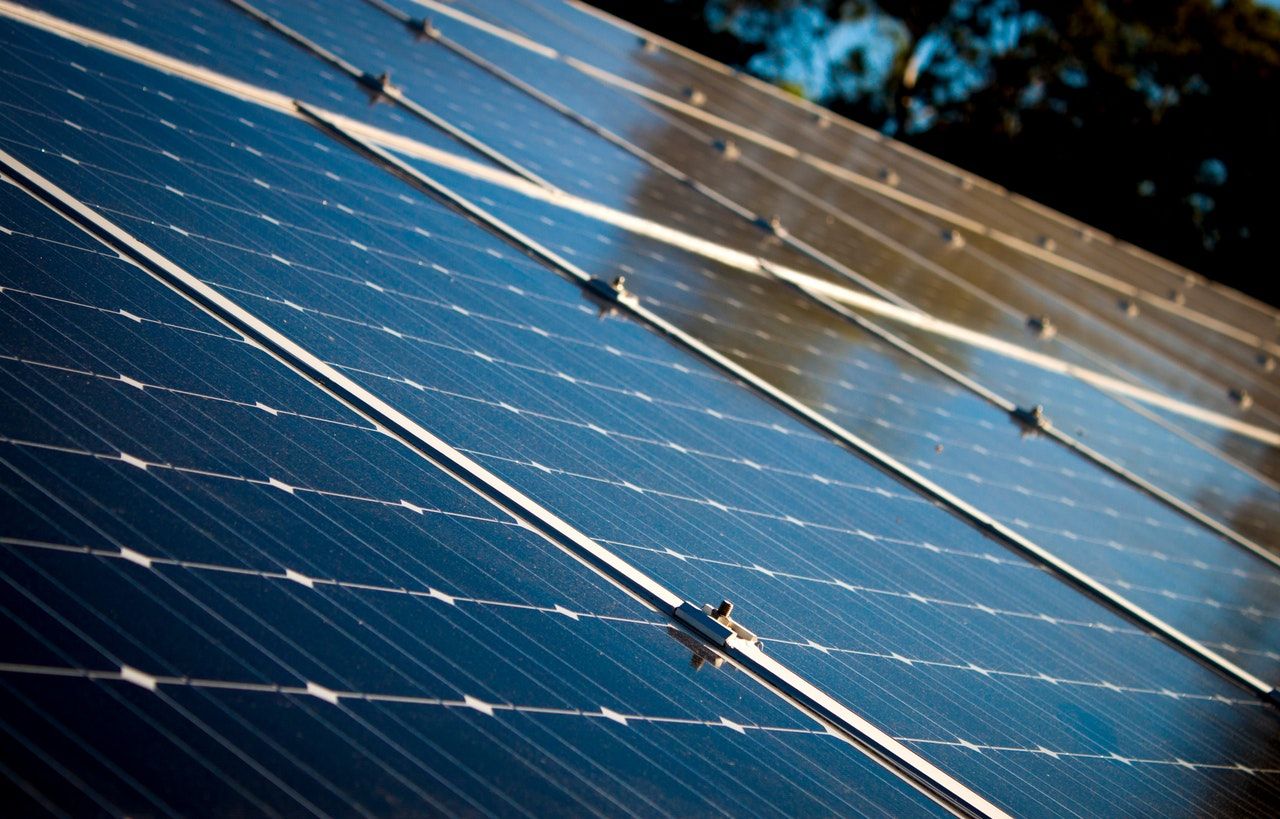 Solar panels cover a roof, reflecting warm sunlight.