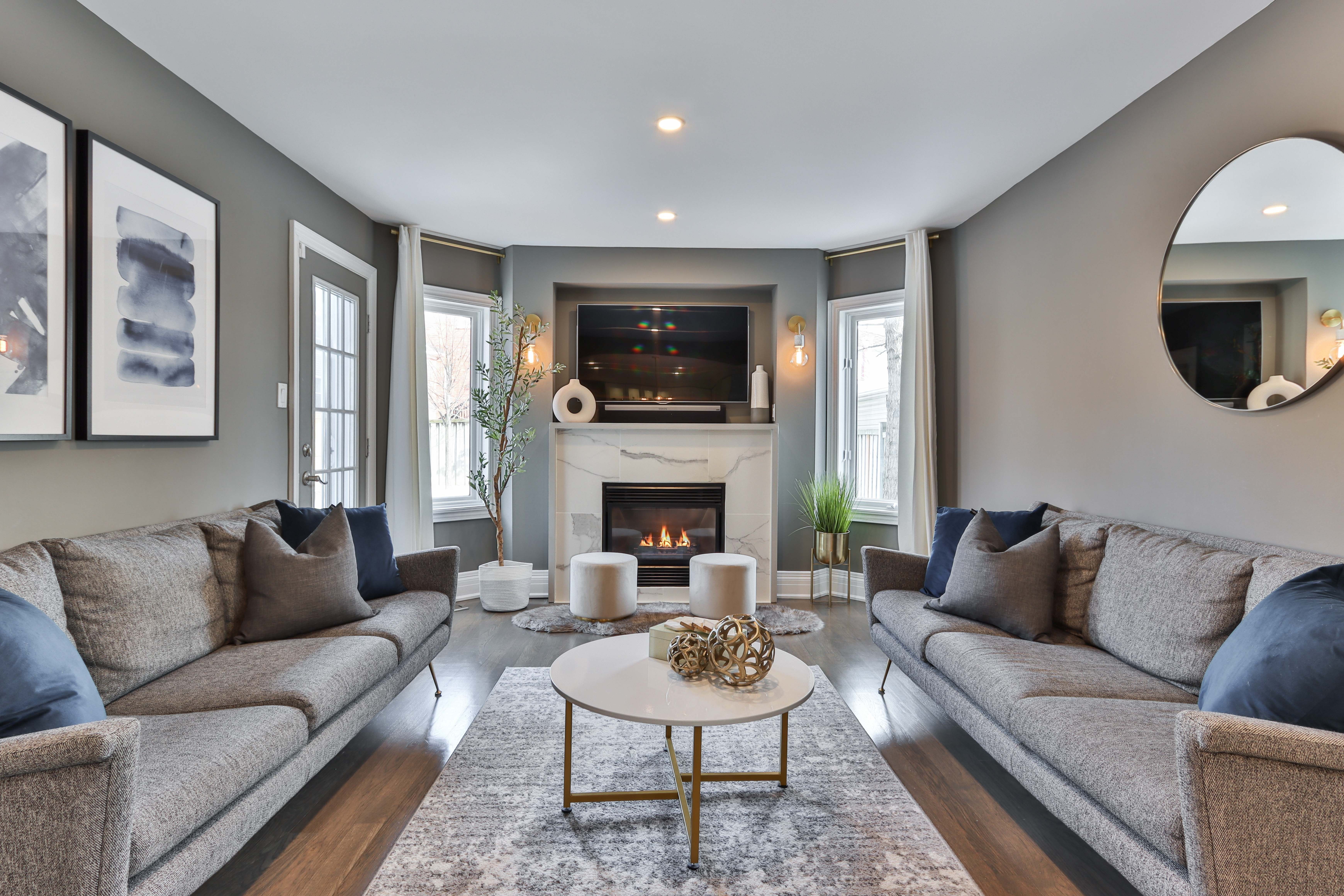Living room with matching gray sofas, a marble fireplace, and a wall-mounted television.