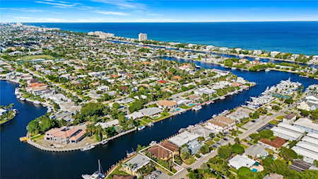 Aerial view of Lighthouse Point homes along winding canals beside the ocean.