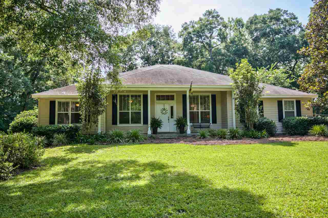 A serene home nestled in the woods, featuring a spacious yard surrounded by lush greenery and tall trees.