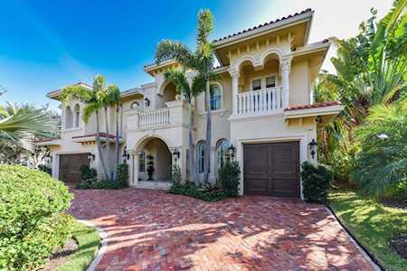 Two-story stucco home with arched balconies, terracotta roof tiles, and a brick-paved driveway.