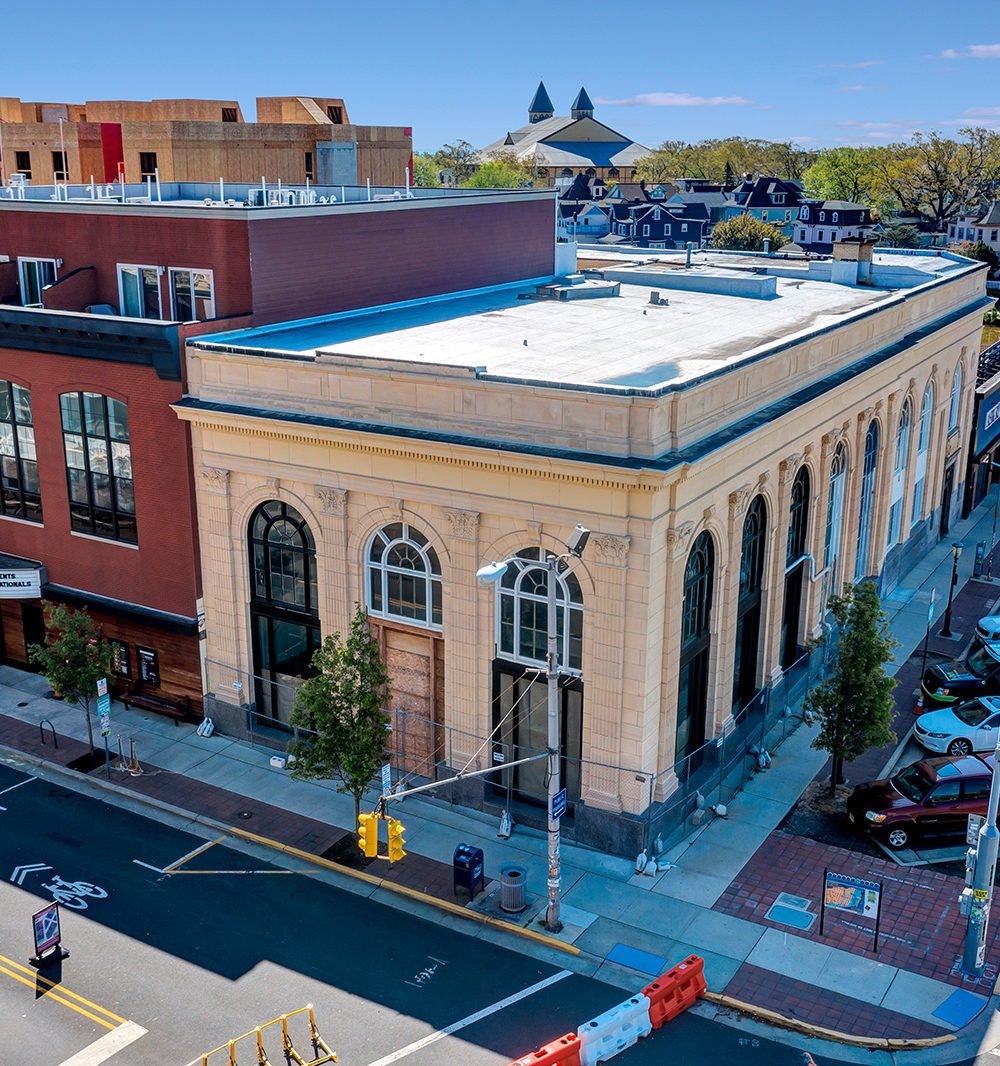 Cream-colored historic corner building with arched windows and a flat roof, viewed from above.