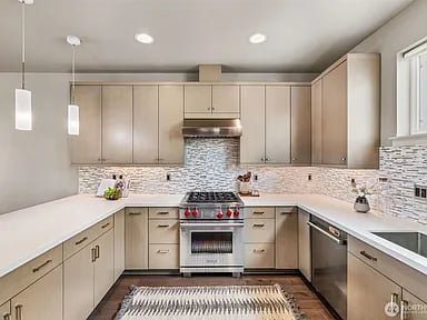 U-shaped kitchen with taupe cabinets, stainless steel appliances, and a mosaic tile backsplash.