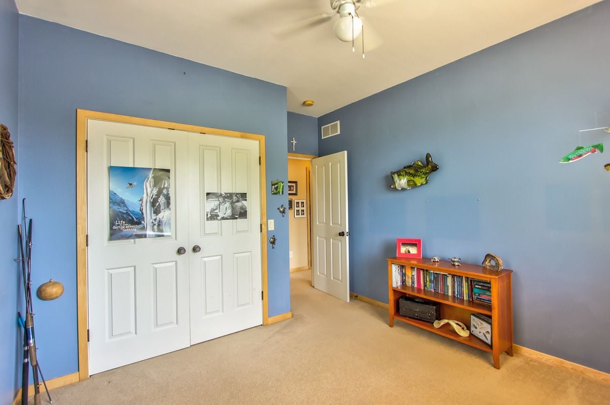 Blue bedroom with white double closet doors, a wooden bookcase, and fishing-themed decorations.