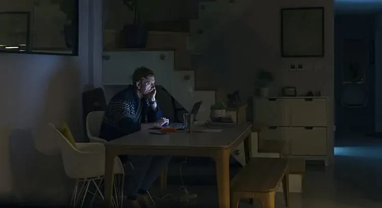 A person working late at night on a computer, with a dimly lit room, suggesting a theme of working late hours or dedication to work.