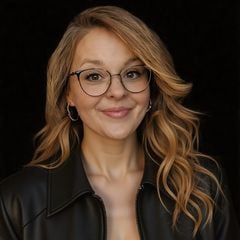 Jessica Weiser wearing glasses and a black leather jacket against a dark background.