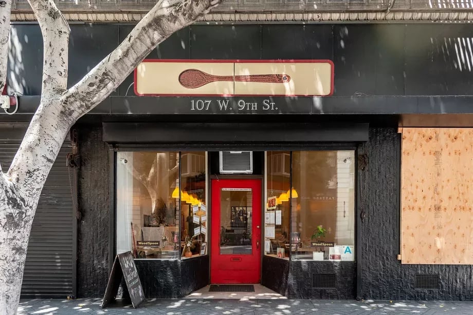 WoodSpoon restaurant storefront with a red entrance door and a large tree in front.