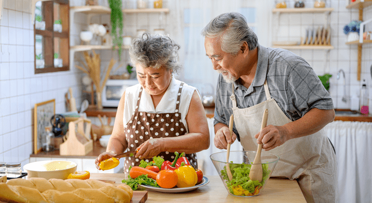 An older couple joyfully preparing a meal together in a cozy kitchen, surrounded by fresh ingredients and cooking utensils.