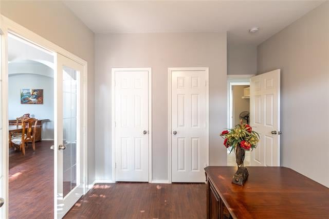 Hallway with dark hardwood floors, white paneled doors, and a wood console topped with flowers.