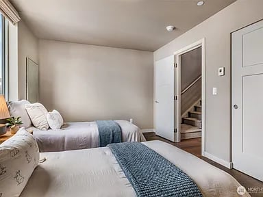 Bedroom with two beds and an open doorway to a staircase.