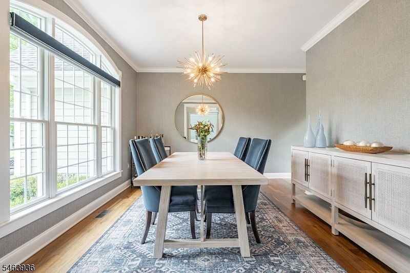 Dining room with a light-wood table, dark chairs, large gridded windows, and a starburst chandelier.