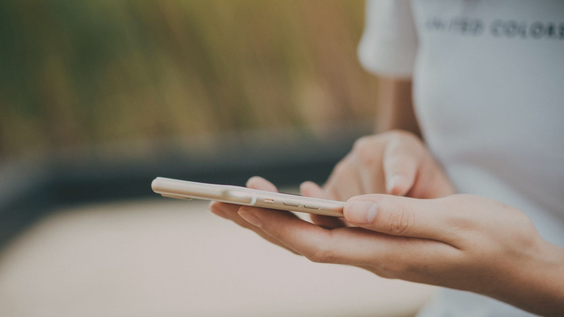 Hands holding and using a smartphone with its screen turned away.