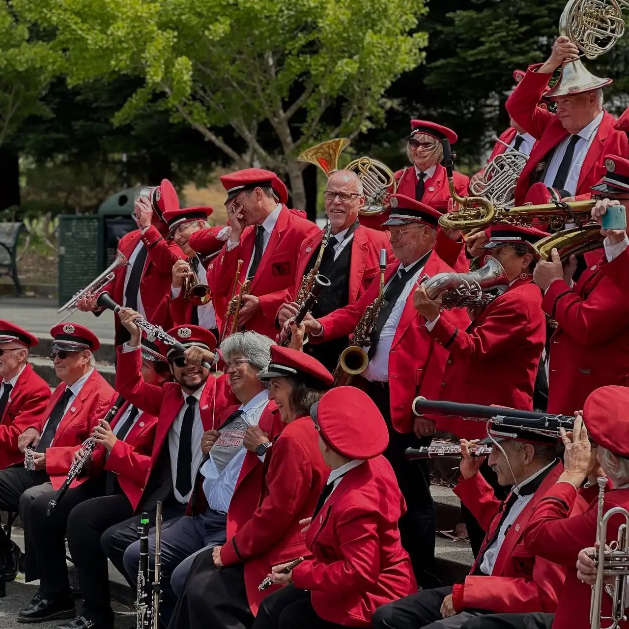 close-up of the Golden Gate Park Band members, with the Golden Gate Park scenery in the background.