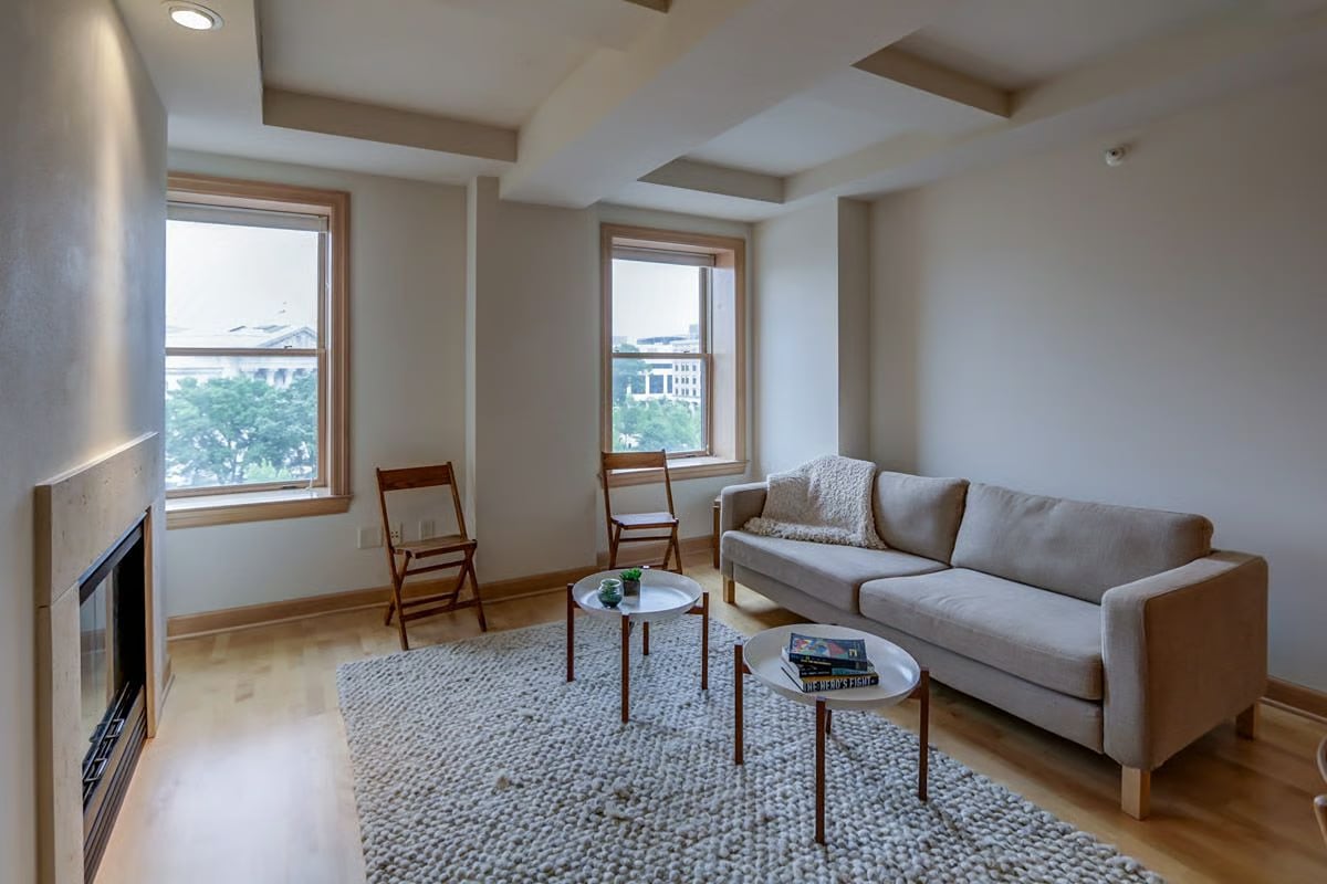 Living room with two city-view windows, a gray sectional sofa, and a fireplace.