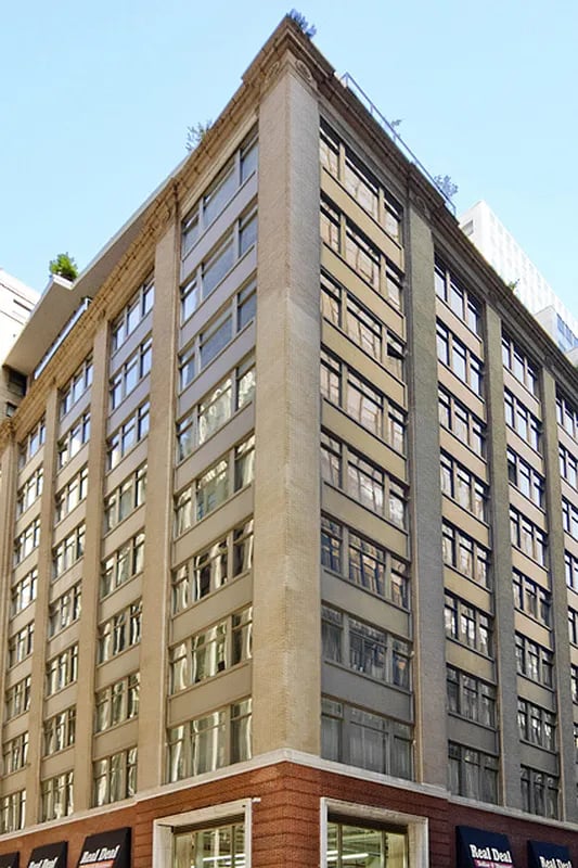 59 John Street, a multi-story corner building with rows of windows and a red-brick storefront.