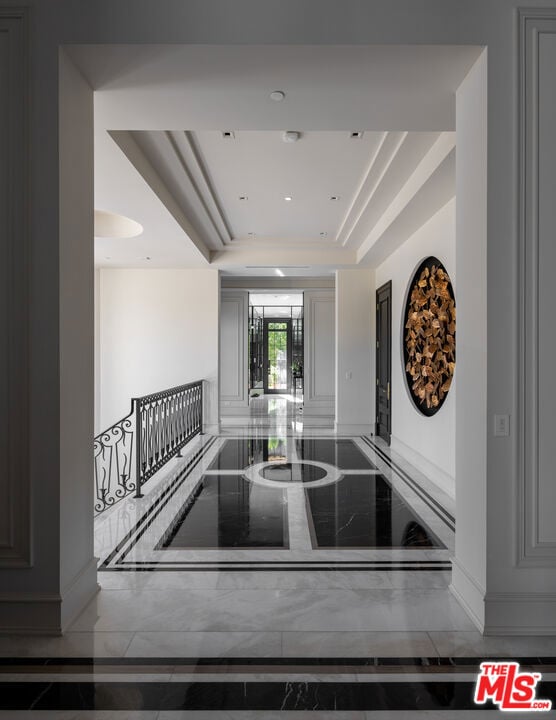 Entry hall with a polished marble floor, ornate railing, and circular gold-toned wall sculpture.